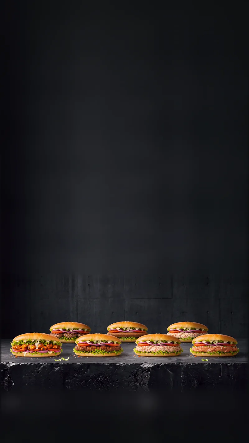 Des sandwichs dans le pain long au sésame : viande grillée, salade, tomate, oignon rouge et sauce blanche